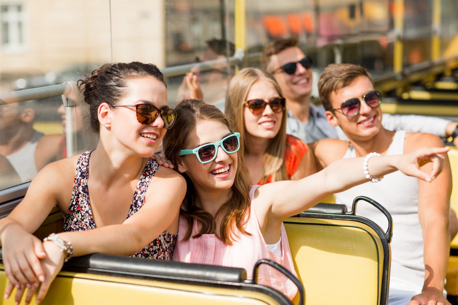 Laughing friends in sunglasses riding together on vacation